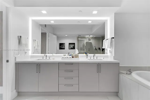 a bathroom with a double vanity sink mirror and bathtub