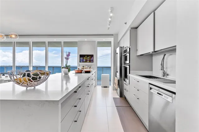 a large white kitchen with a large window and stainless steel appliances