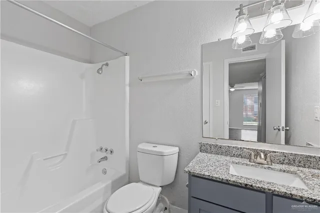 a bathroom with a granite countertop toilet a sink and a mirror