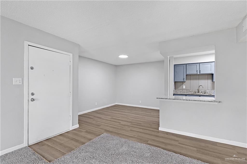 2425 Barnard Road, Unit UJNIT 1A Brownsville, TX 78520 - Photo 2 of 16 Unfurnished living room featuring a sink, baseboards, and wood finished floors