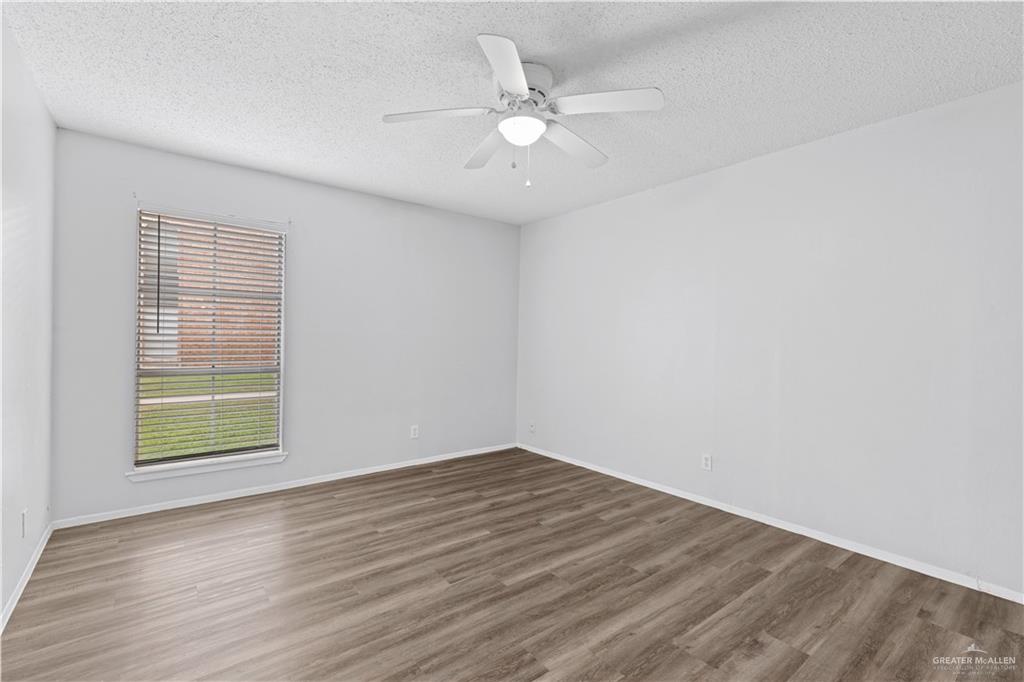 2425 Barnard Road, Unit UJNIT 1A Brownsville, TX 78520 - Photo 7 of 16 Empty room with baseboards, a textured ceiling, and wood finished floors