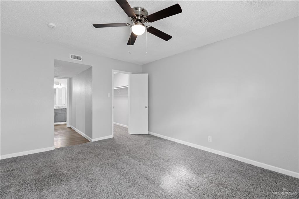 2425 Barnard Road, Unit UJNIT 1A Brownsville, TX 78520 - Photo 8 of 16 Unfurnished bedroom featuring a textured ceiling, visible vents, a spacious closet, carpet floors, and baseboards