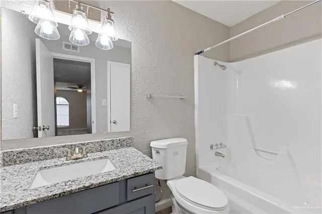 a bathroom with a granite countertop sink a toilet and a mirror