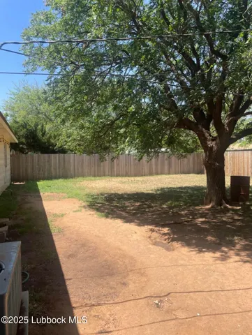 a view of a yard with an tree and wooden fence