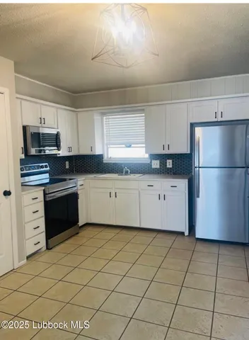 a kitchen with granite countertop a refrigerator sink and white cabinets