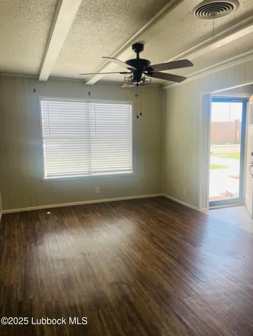 an empty room with wooden floor fan and windows