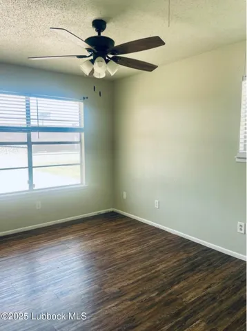 an empty room with wooden floor fan and windows