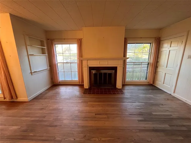 a view of a livingroom with wooden floor and a fireplace
