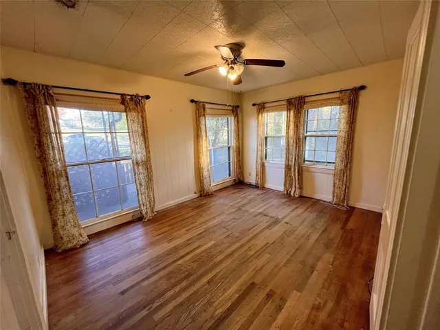 a spacious bedroom with a bed a dresser and wooden floor