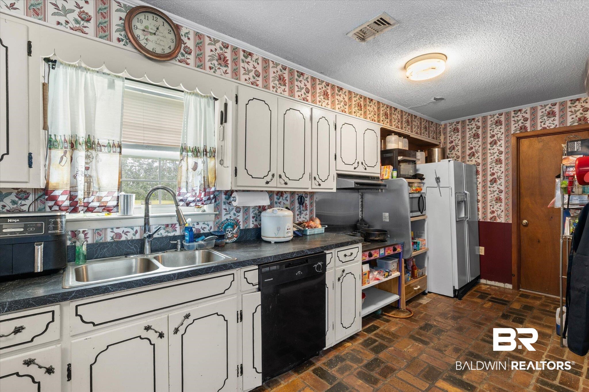 11601 Lott Road Chunchula, AL 36521 - Photo 7 of 34 Kitchen featuring wallpapered walls, dark countertops, black dishwasher, white fridge with ice dispenser, and a textured ceiling