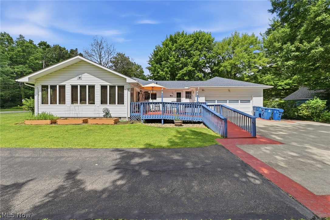 1499 Morris Road Kent, OH 44240 - Photo 38 of 41 White siding exterior featuring a multi-pane sunroom, expansive blue deck, and a multi-car driveway with a red-accented ramp