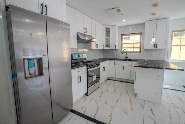 a kitchen with granite countertop a refrigerator a sink and cabinets