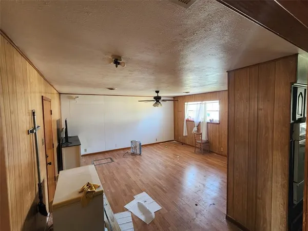 a view of empty room with wooden floor and fan