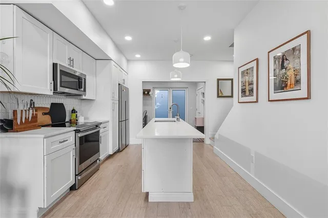 a kitchen with stainless steel appliances a microwave a stove a sink dishwasher and a refrigerator with wooden floor