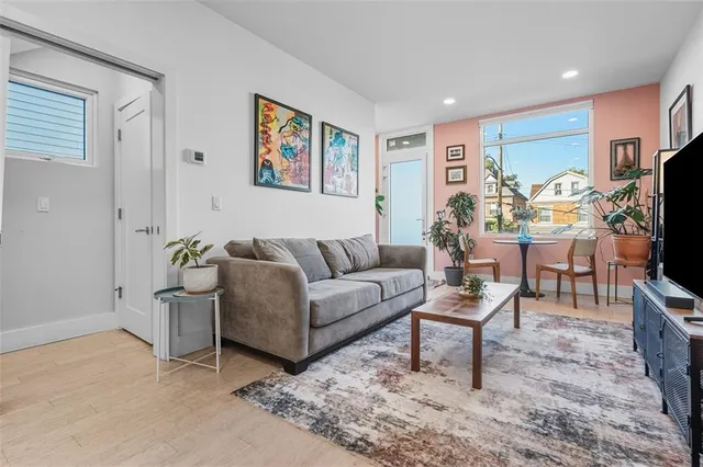 a living room with furniture a flat screen tv and a refrigerator