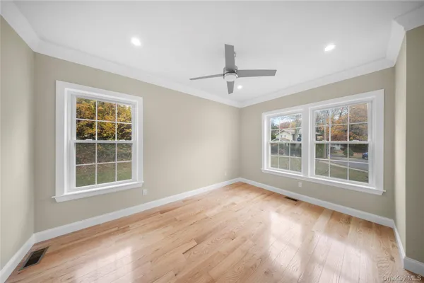 a view of an empty room with a window and wooden floor
