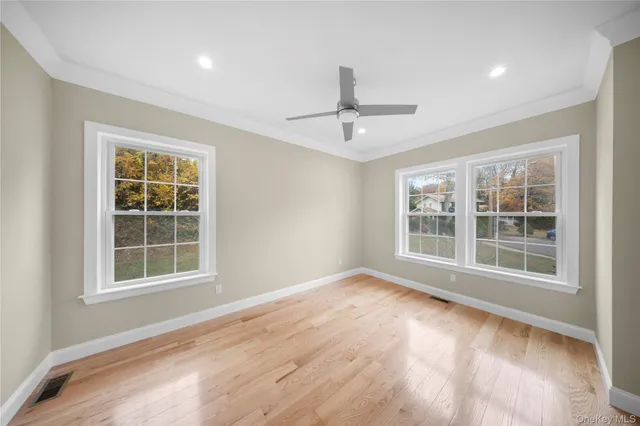 a view of an empty room with a window and wooden floor