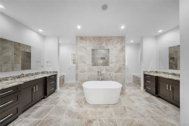a spacious bathroom with a tub sink and mirror