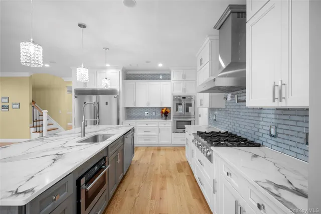 a large kitchen with stainless steel appliances kitchen island granite countertop a lot of counter space and wooden floors