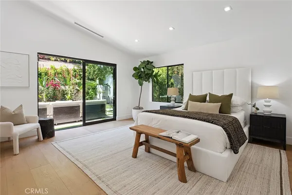a large white bed sitting in a bedroom next to a window