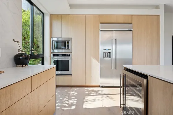 a kitchen with a dining table chairs stainless steel appliances and wooden floor