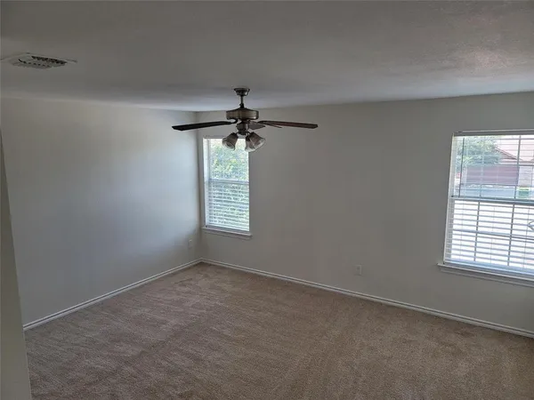 an empty room with windows and chandelier fan