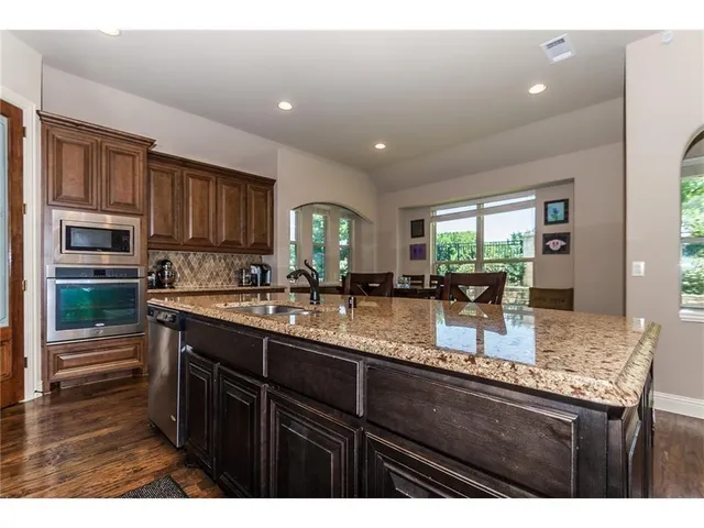 a kitchen with kitchen island granite countertop a sink window and cabinets