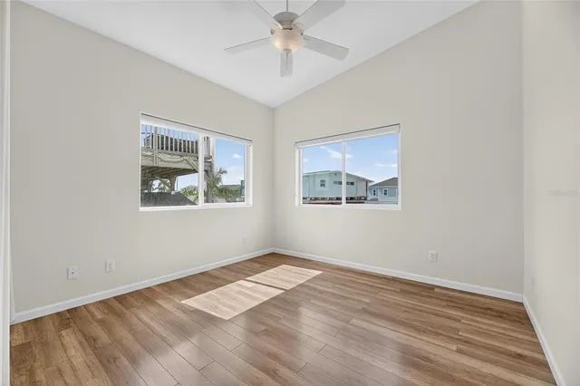 a view of empty room with wooden floor and fan