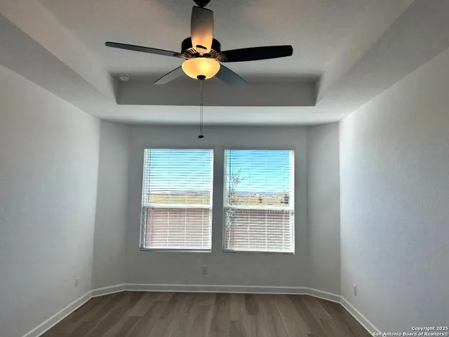 a view of an empty room with window and chandelier fan