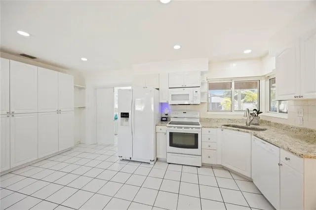 a kitchen with granite countertop white cabinets and white appliances