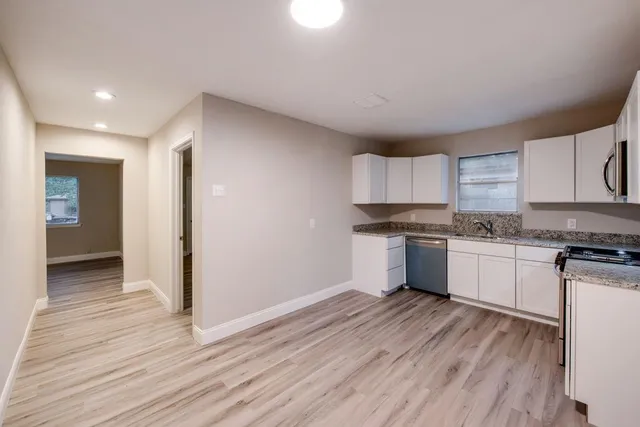 a kitchen with granite countertop wooden floors and white stainless steel appliances