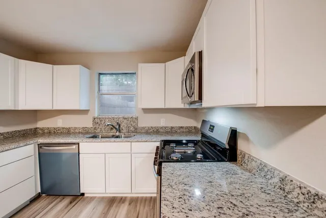 a kitchen with stainless steel appliances granite countertop a sink stove and cabinets