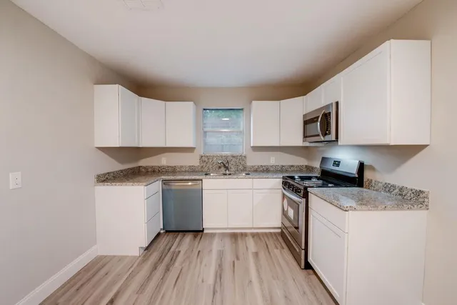 a kitchen with a sink a stove top oven and white kitchen