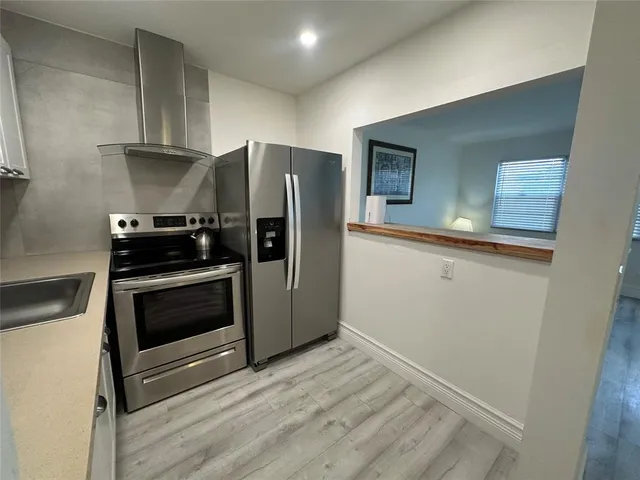 a kitchen with granite countertop a refrigerator and a stove top oven