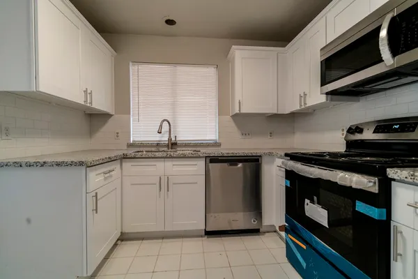a kitchen with stainless steel appliances granite countertop a sink stove and microwave