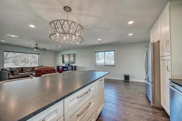 a living room with stainless steel appliances furniture a chandelier and a view of kitchen
