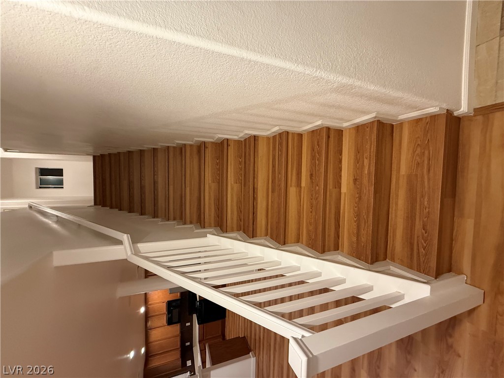 A classic wooden staircase is complemented by a clean white railing and crisp plaster walls.