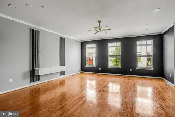 a view of an empty room with window and wooden floor