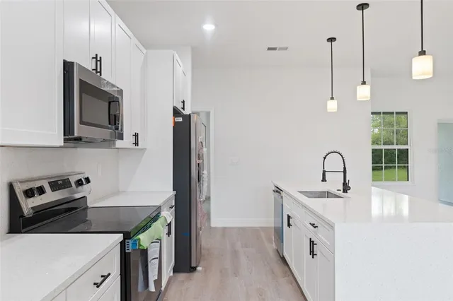 a kitchen that has a sink a microwave a refrigerator and a stove