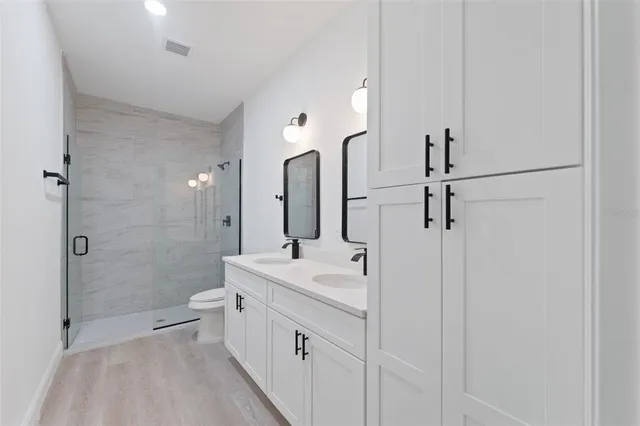 a bathroom with a double vanity sink toilet mirror and shower