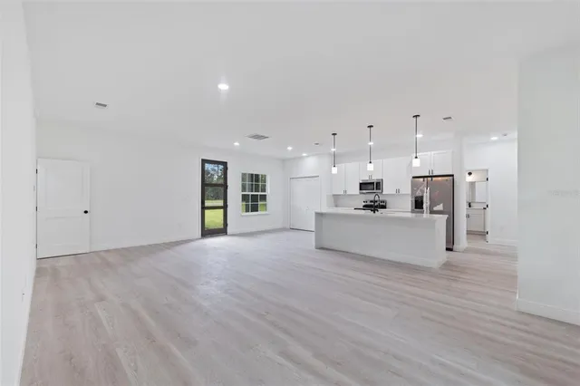 a view of a kitchen with kitchen island a sink wooden floor and a refrigerator