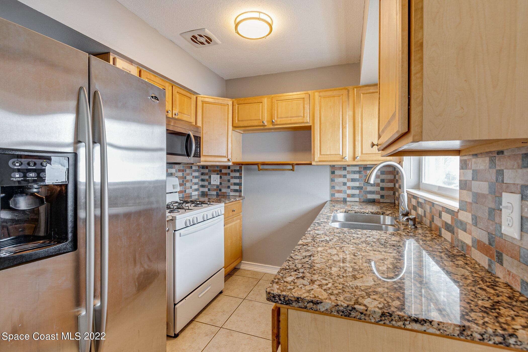 714 Catalina Road, Unit 9 Cocoa Beach, FL 32931 - Photo 4 of 33 a kitchen with stainless steel appliances granite countertop a refrigerator and a stove