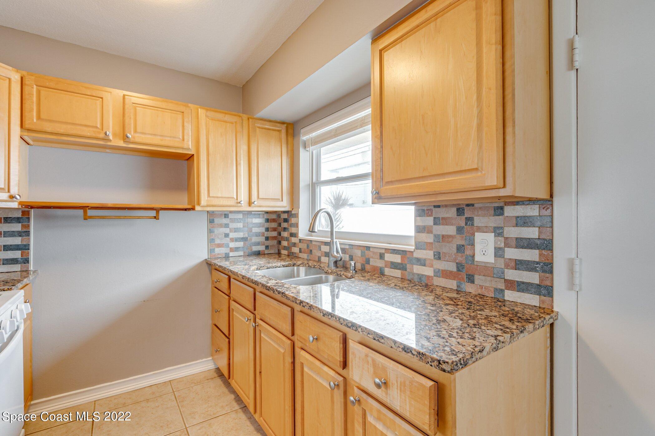 714 Catalina Road, Unit 9 Cocoa Beach, FL 32931 - Photo 5 of 33 a kitchen with stainless steel appliances granite countertop a sink stove and cabinets
