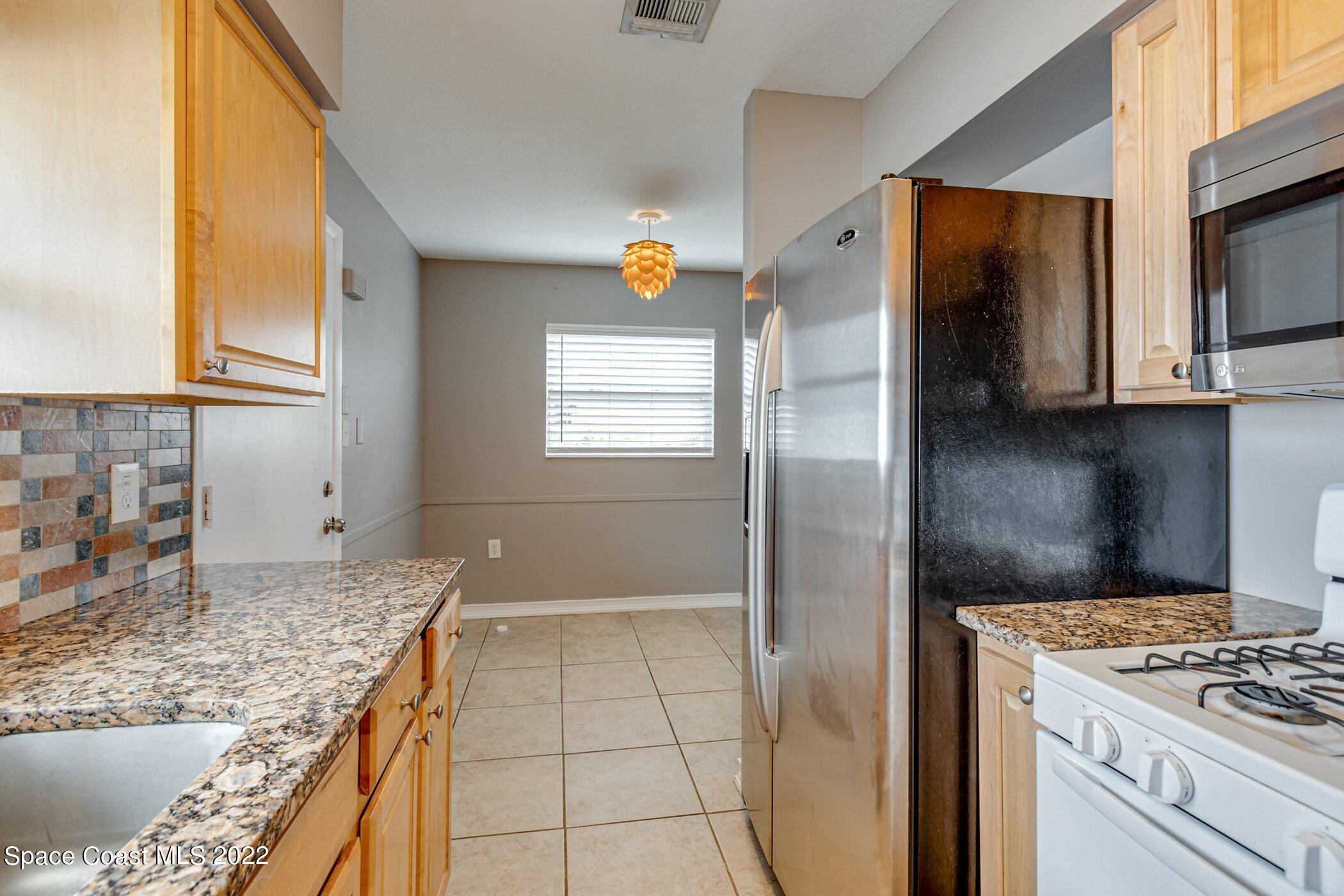 714 Catalina Road, Unit 9 Cocoa Beach, FL 32931 - Photo 7 of 33 a kitchen with stainless steel appliances granite countertop a refrigerator and a stove