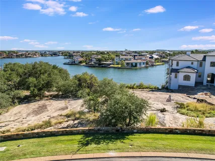 an aerial view of residential houses with outdoor space and lake view in back