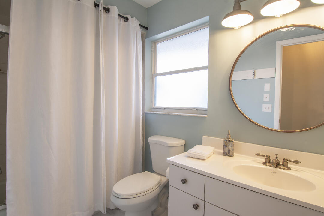 3372 Southeast Court Drive Stuart, FL 34997 - Photo 15 of 33 a bathroom with a sink a mirror a toilet and a window