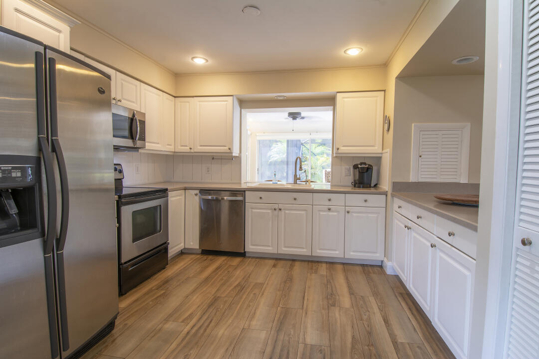 3372 Southeast Court Drive Stuart, FL 34997 - Photo 26 of 33 a kitchen with stainless steel appliances a sink cabinets and a wooden floor