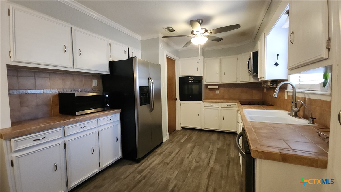 204 Cherokee Lane Victoria, TX 77901 - Photo 5 of 14 a kitchen with granite countertop a refrigerator a sink dishwasher and white cabinets with wooden floor
