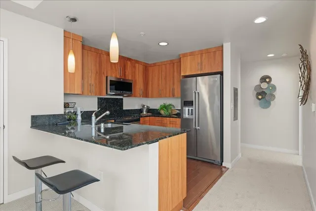 a kitchen with stainless steel appliances granite countertop a refrigerator a stove a sink and a microwave