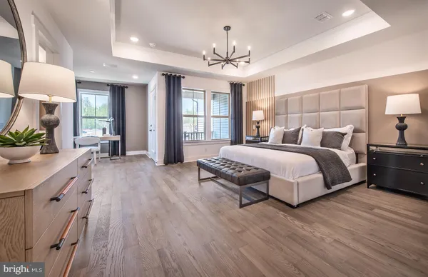 a spacious bedroom with a large bed a chandelier and windows